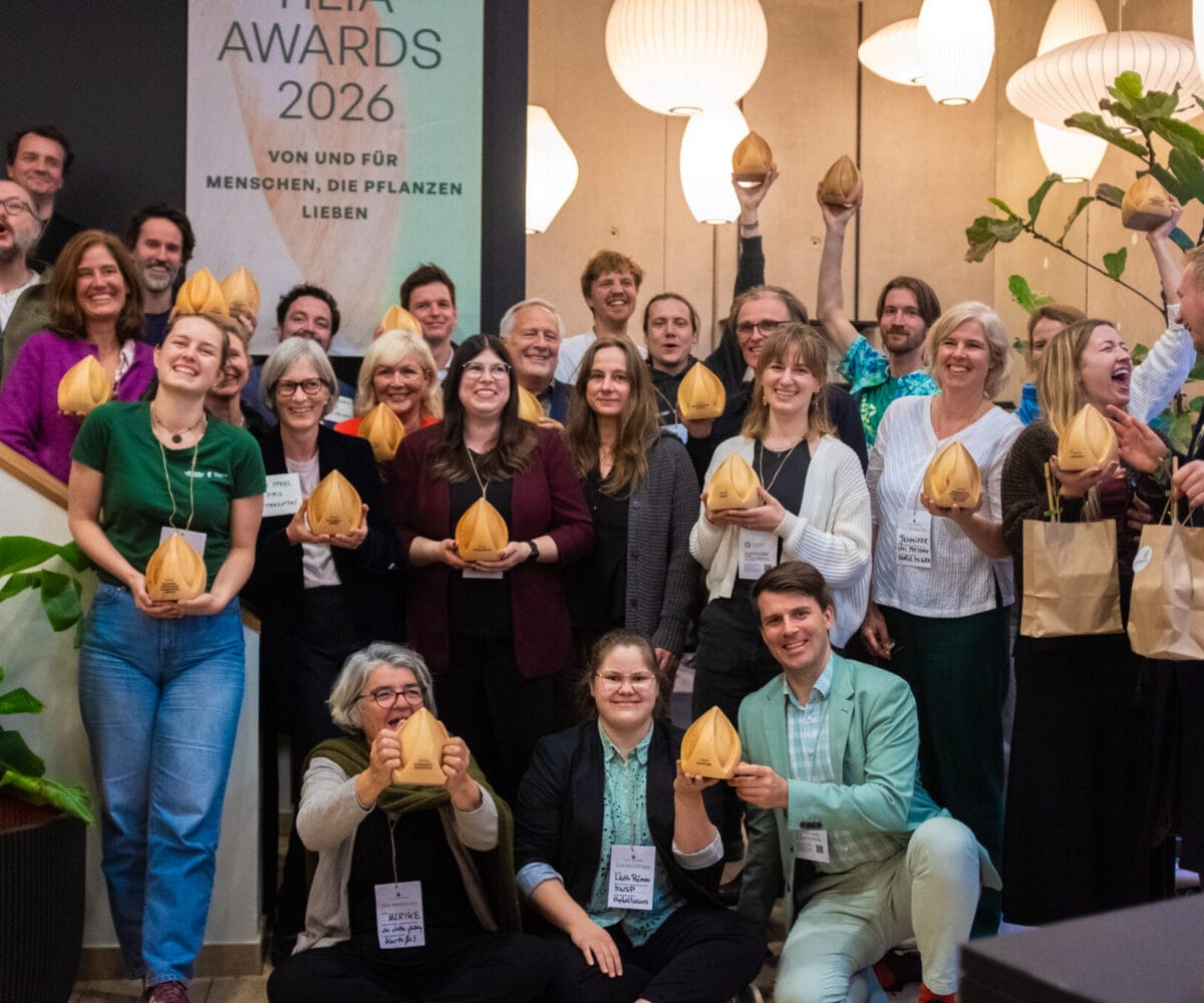 Gruppenszene mit Gewinnerinnen der Tilia Awards 2026, die ihre Auszeichnungen in die Höhe halten, umgeben von Pflanzen.